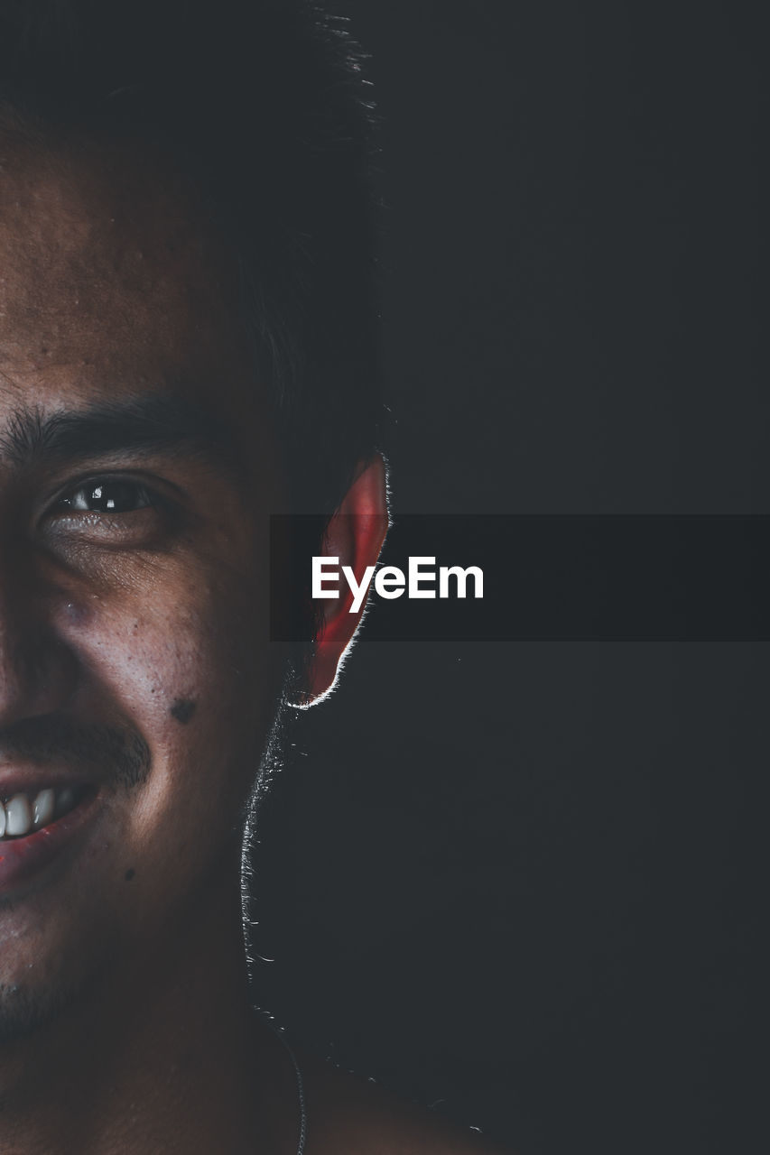 Close-up portrait of young man against black background