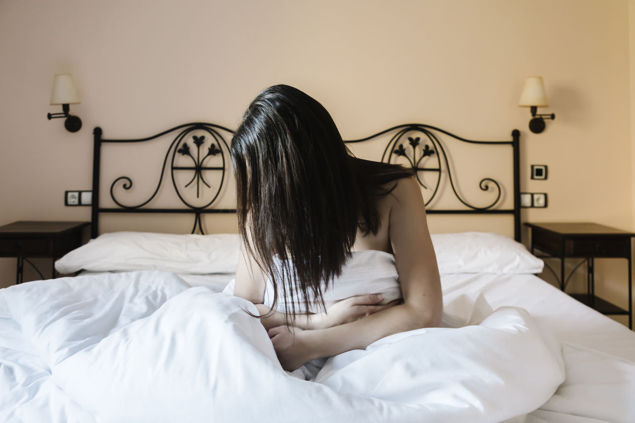 Woman hiding behind her hair in bed