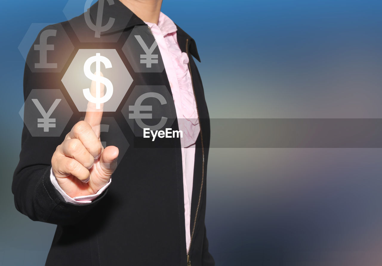 Digital composite image of businessman touching currency symbols on device screen