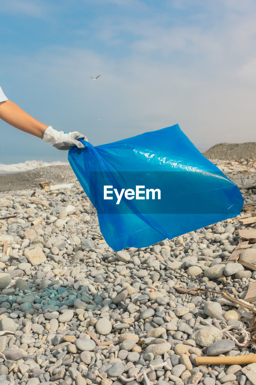 Hand of a young volunteer with an empty bag on a beach. ecology concept