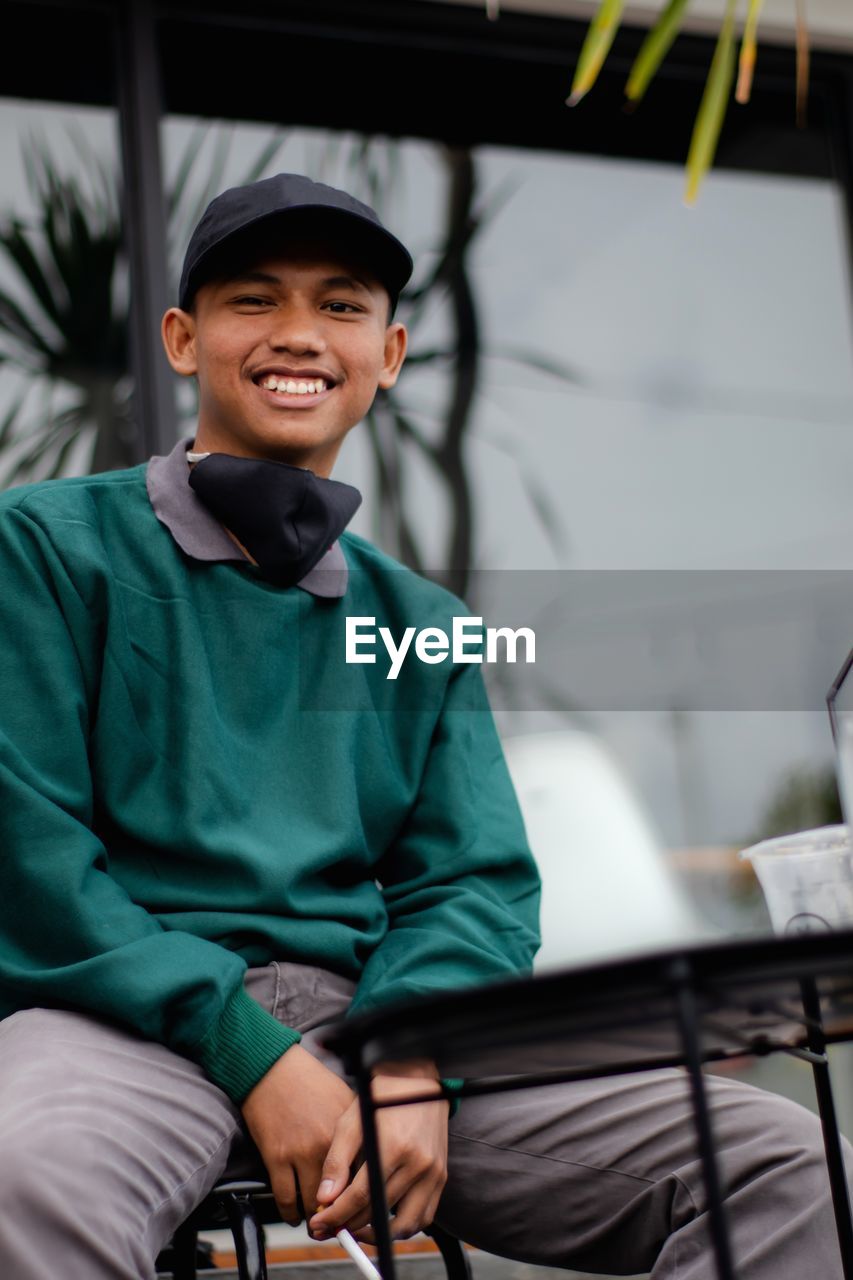 PORTRAIT OF A SMILING BOY SITTING ON A MAN