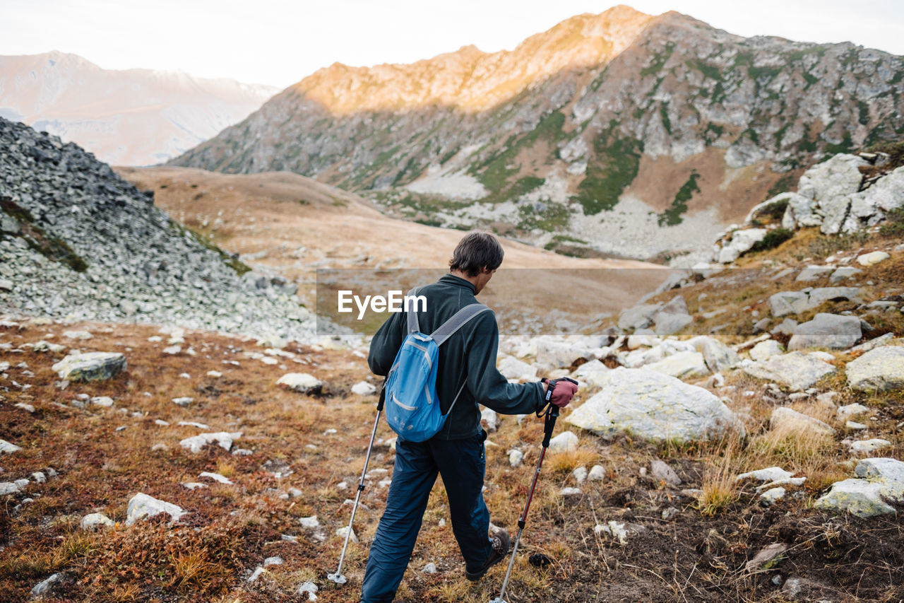 Rear view of male hiker walking on landscape