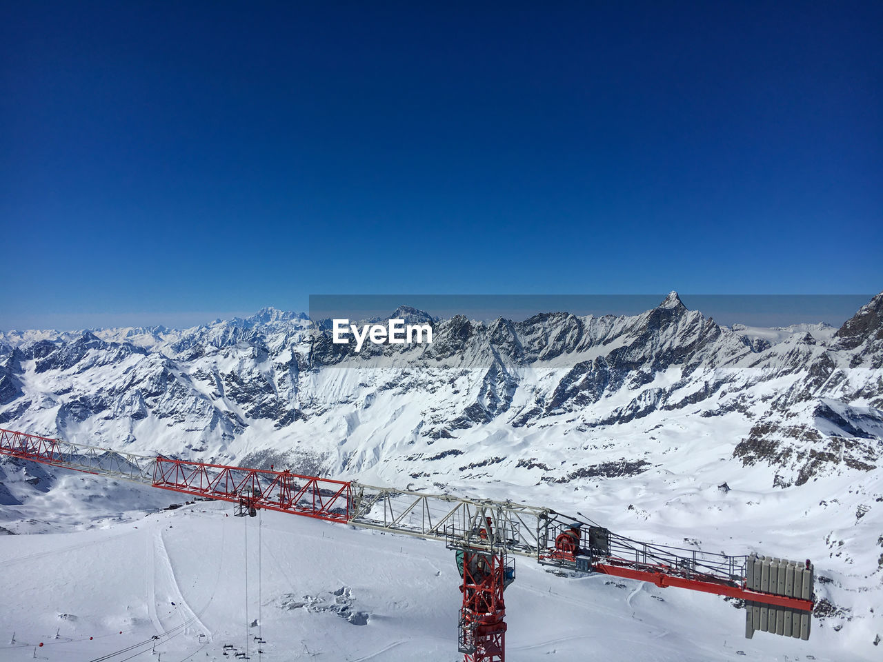Construction crane on top of klein matterhorn with matterhorn  in the background against blue sky