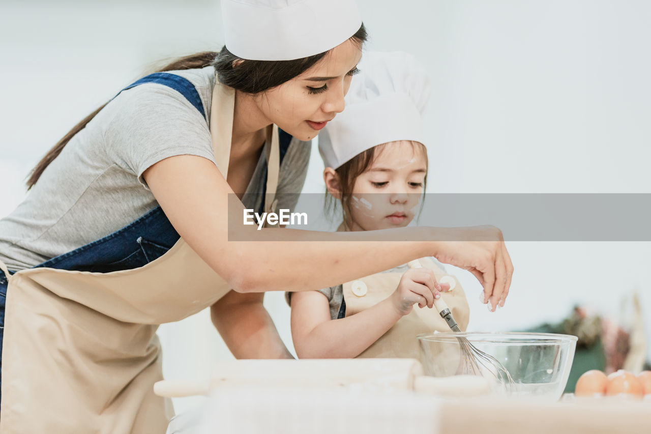 Mother and daughter preparing food on table