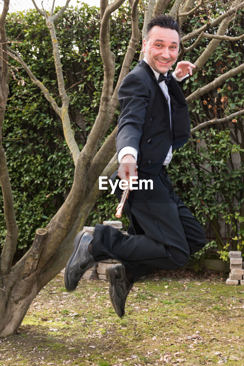 Portrait of happy man with flute jumping in park