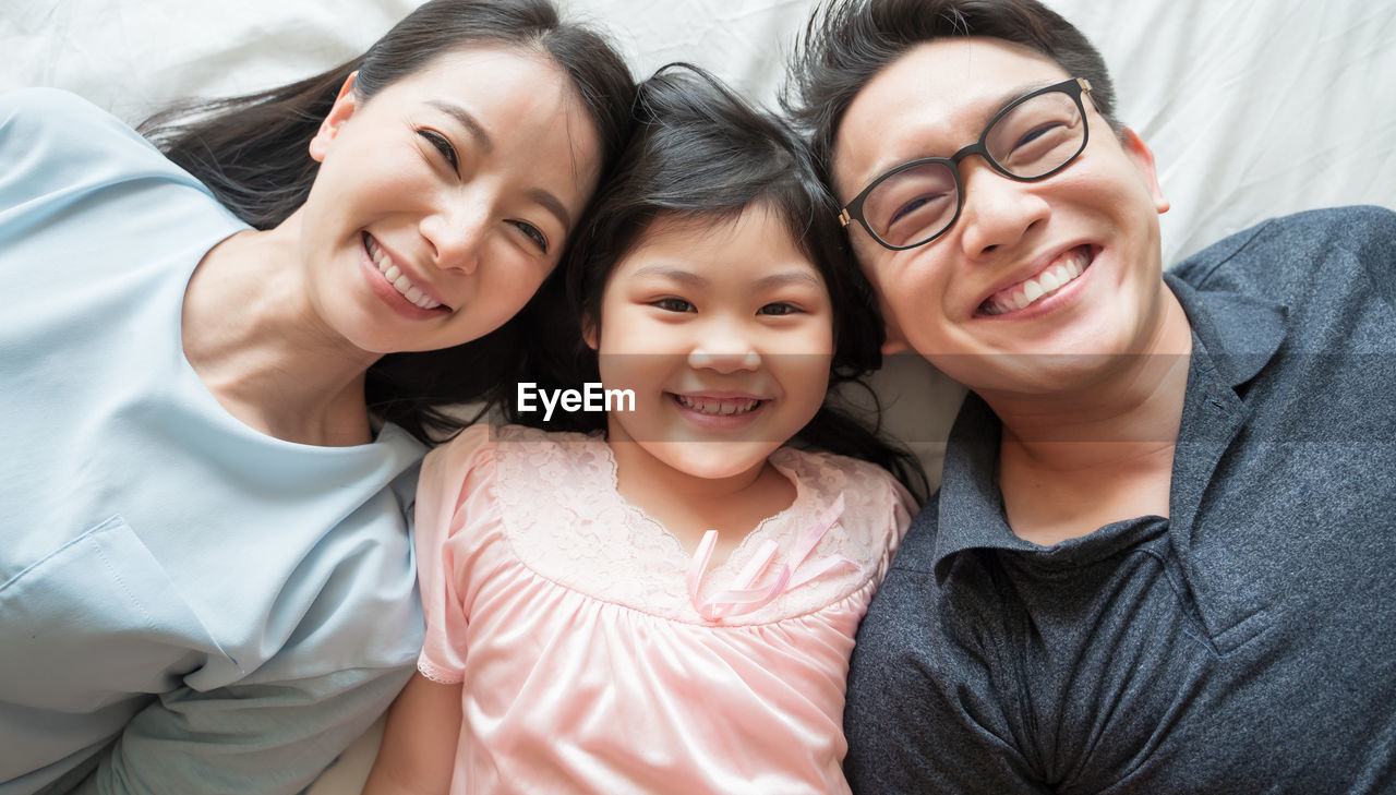 Portrait of smiling family lying on bed at home