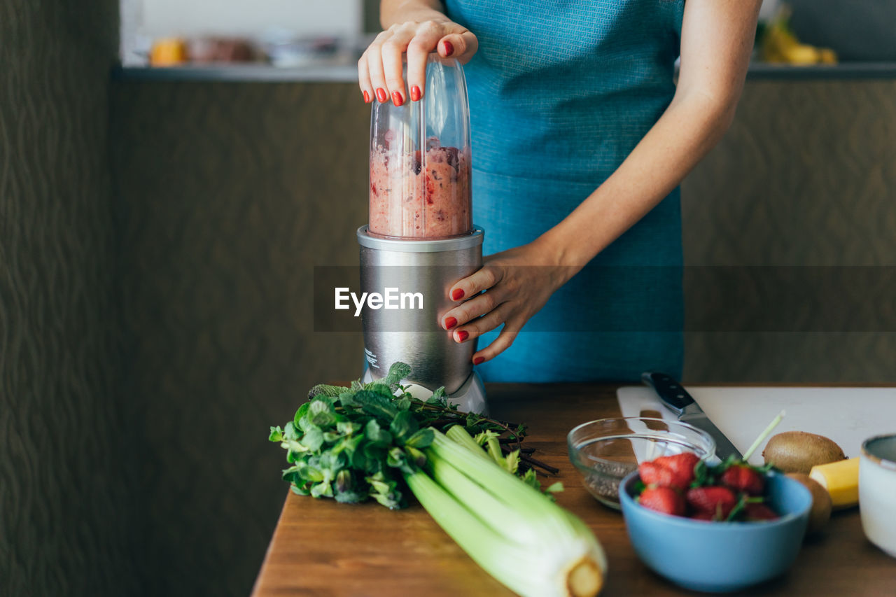 Close-up of a woman making a fruity summer pink smoothie. 