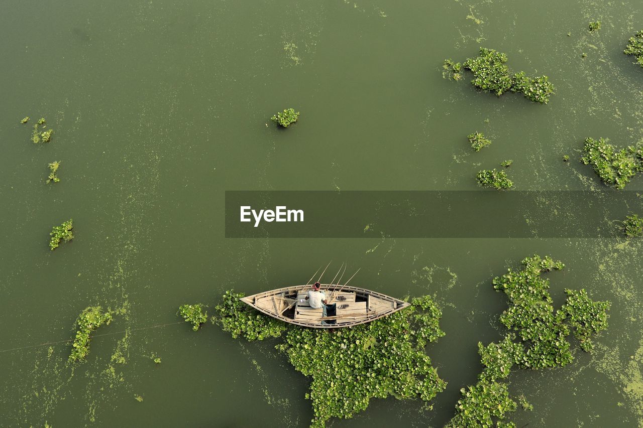 High angle view of boat floating on river and fishing by fishing rod
