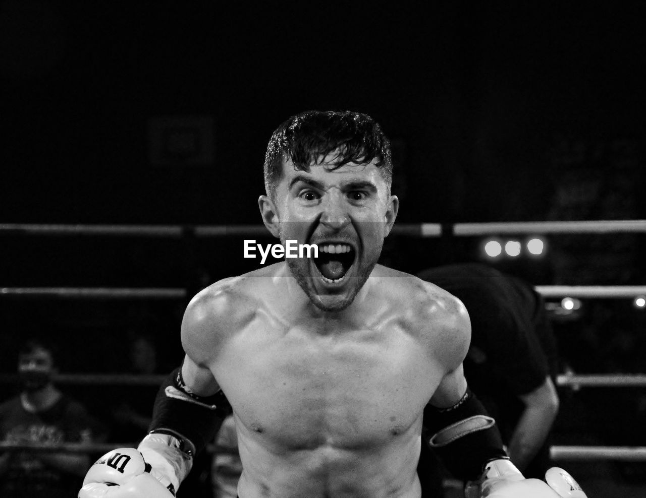 Portrait of shirtless boxer shouting while standing in boxing ring