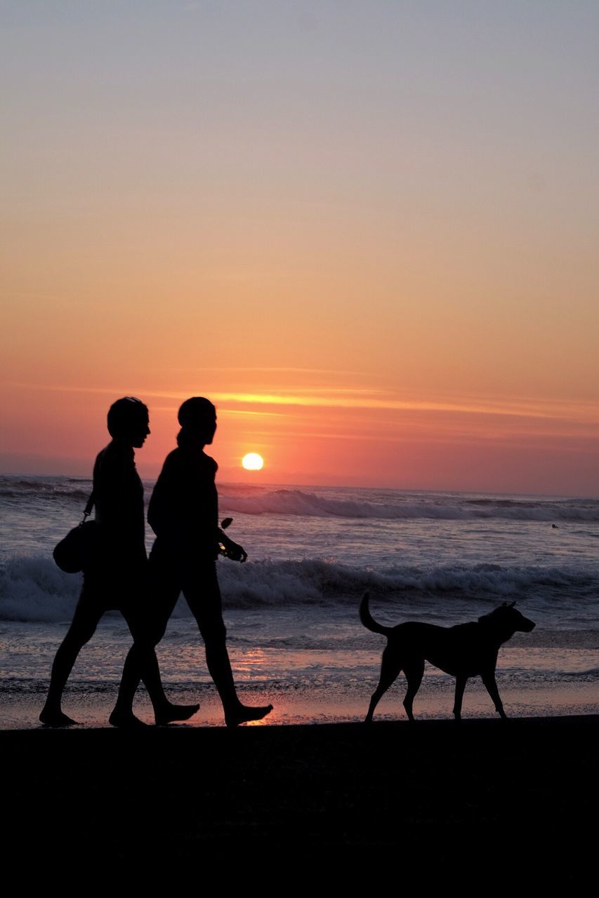 SILHOUETTE OF PEOPLE WALKING ON BEACH AGAINST SKY DURING SUNSET