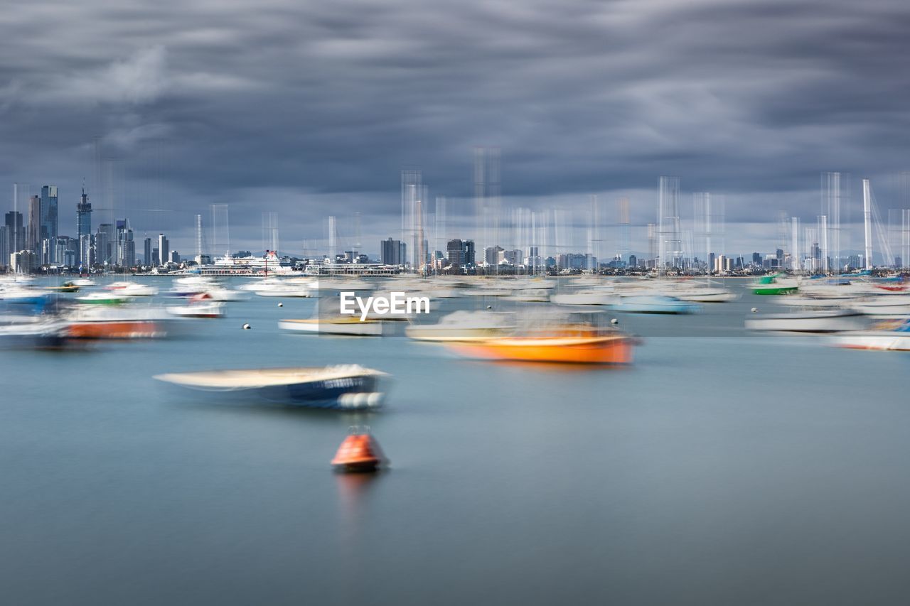 Boats moored at harbor in city against sky