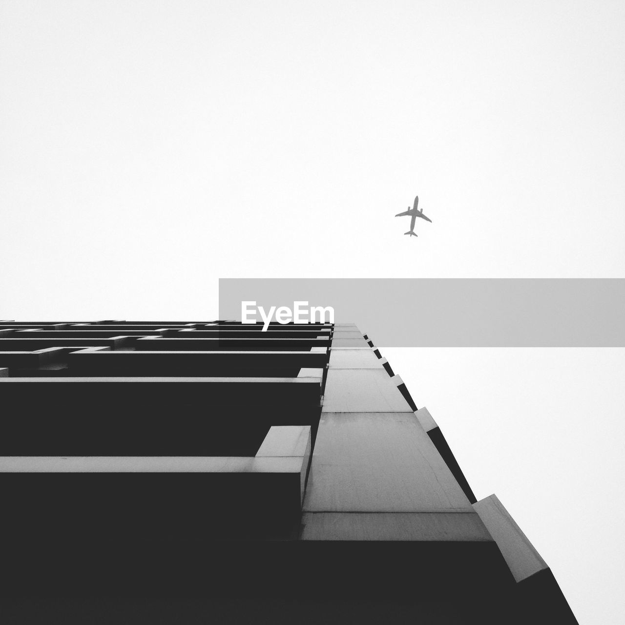 Low angle view of airplane and building against clear sky