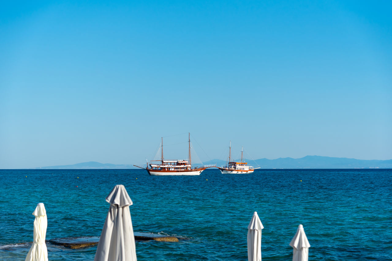 water, sea, nautical vessel, transportation, mode of transportation, sailboat, sky, blue, nature, ocean, sailing, travel, vehicle, clear sky, ship, boat, beauty in nature, scenics - nature, sailing ship, horizon, horizon over water, no people, copy space, day, tranquil scene, tranquility, pole, travel destinations, bay, watercraft, luxury, idyllic, holiday, land, outdoors, mast, beach, vacation, coast, sunny, yacht, trip, sunlight, summer, tourism, environment, seascape, non-urban scene