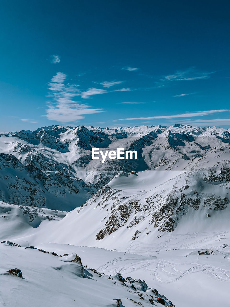 Scenic view of snow covered mountains against blue sky