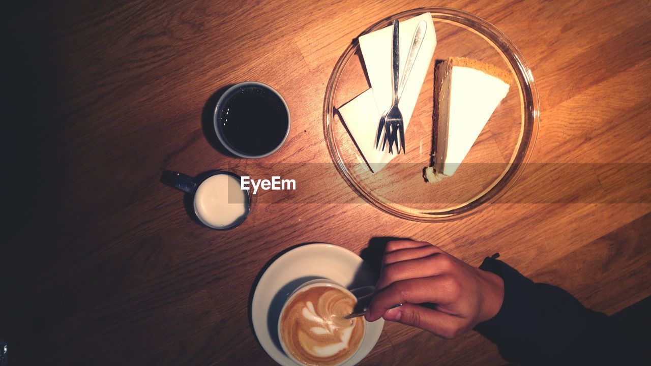 Cropped image of person having coffee and cake on table