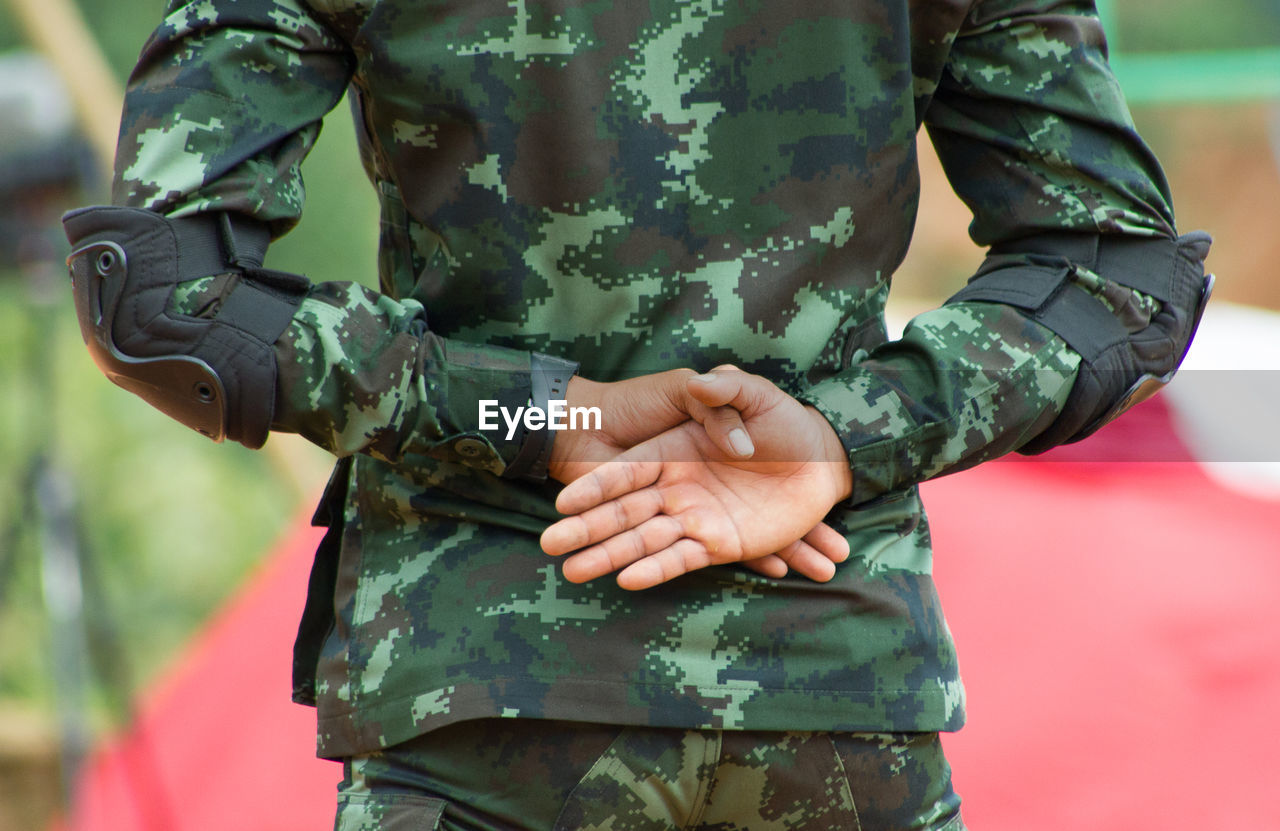 Midsection of army soldier with hands behind back