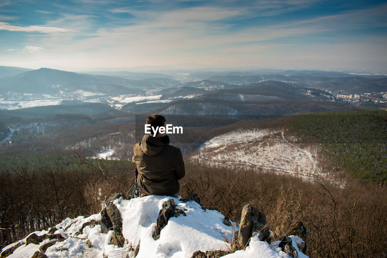 Rear view of man looking at mountain during winter