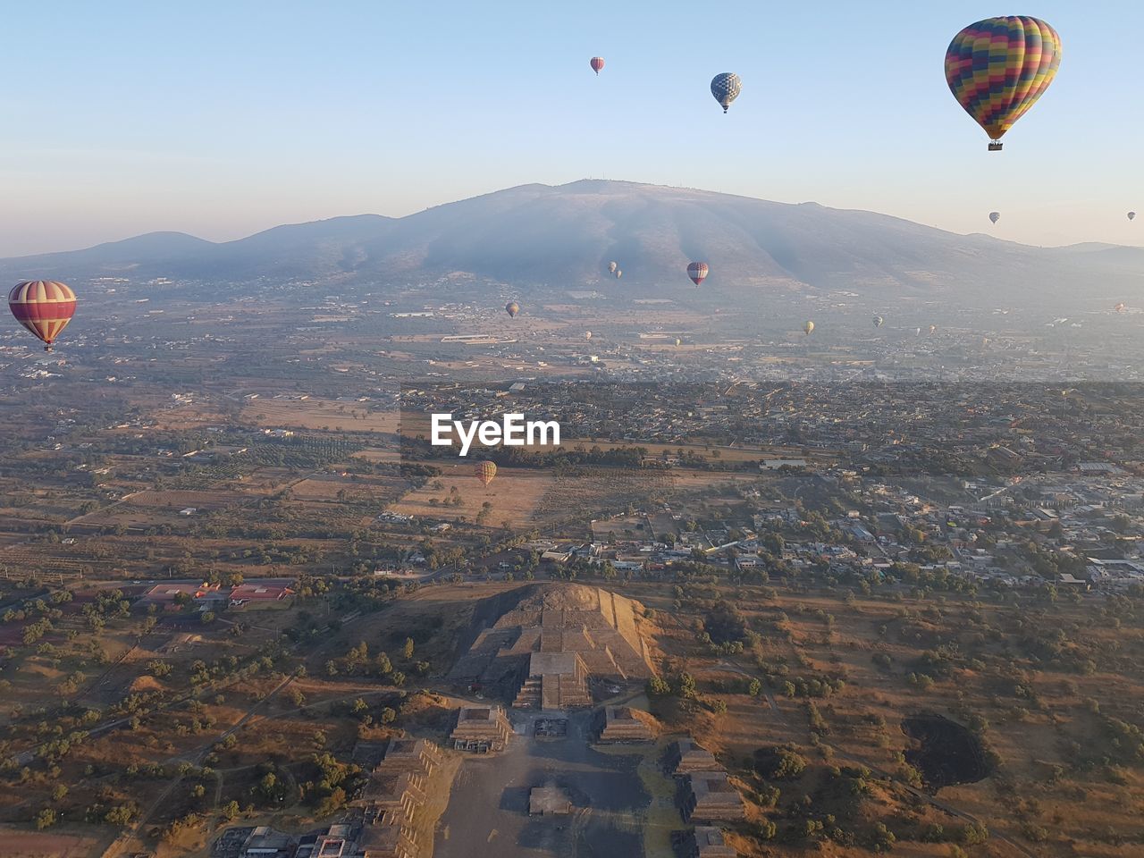 Aerial view of hot air balloons flying over landscape