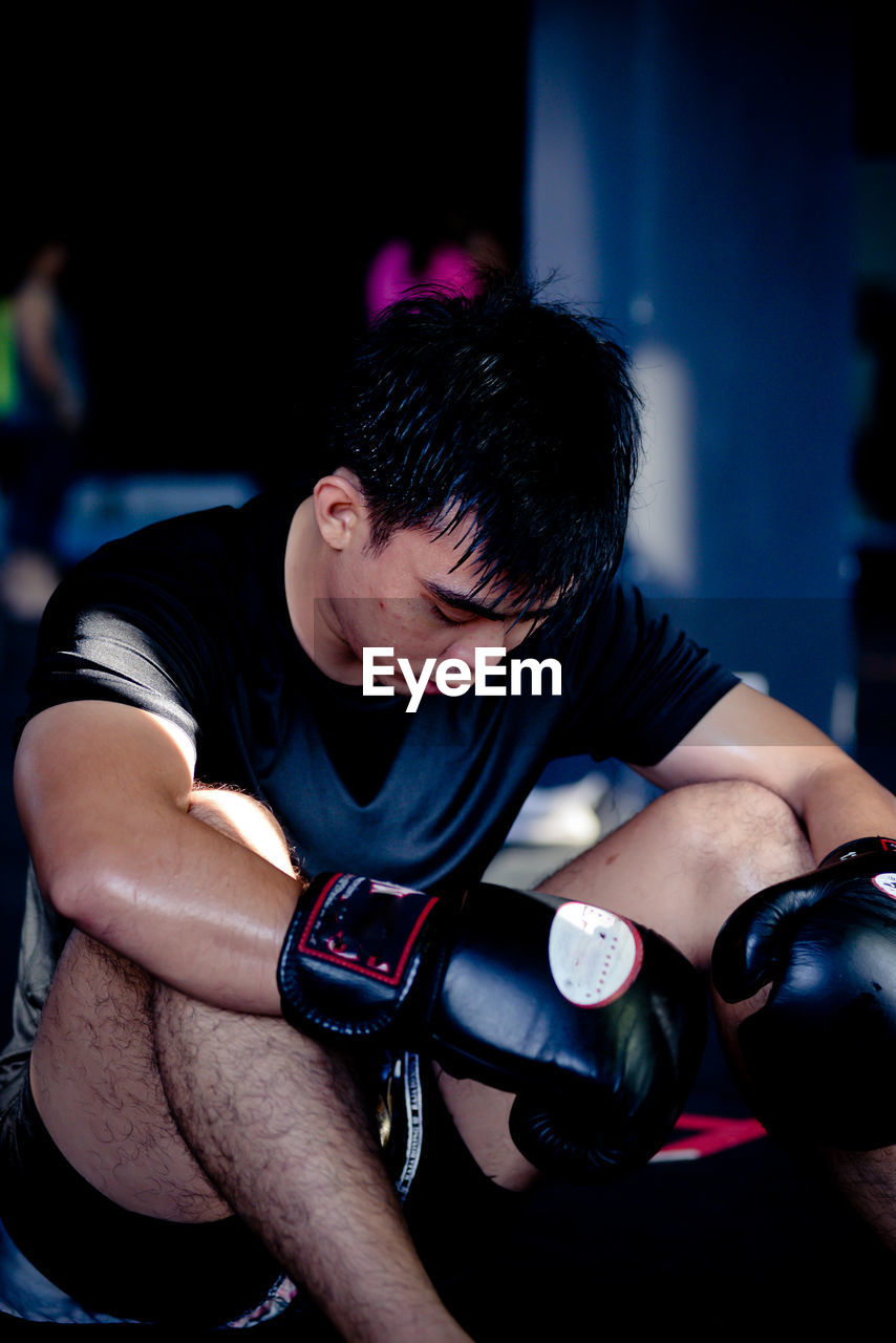 Close-up of boxer looking down while sitting in gym