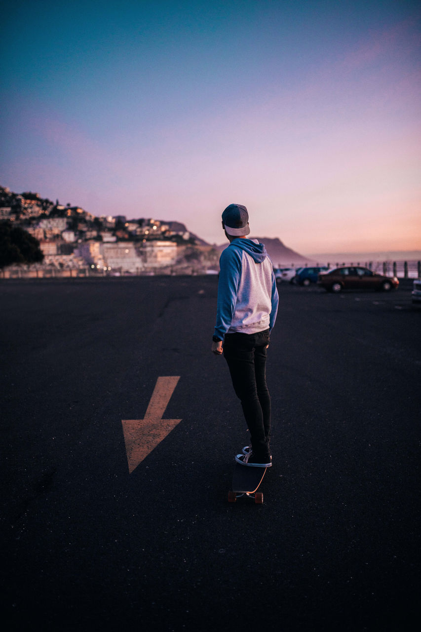 Full length of a man standing on road at sunset