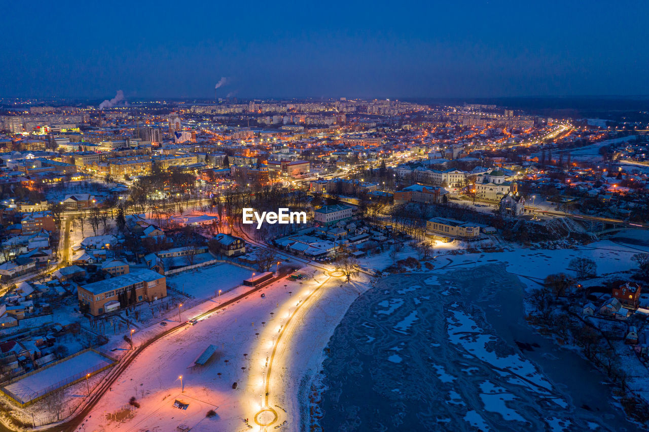 Beautiful evening top view of the city. winter city in the snow. the river is covered with ice.