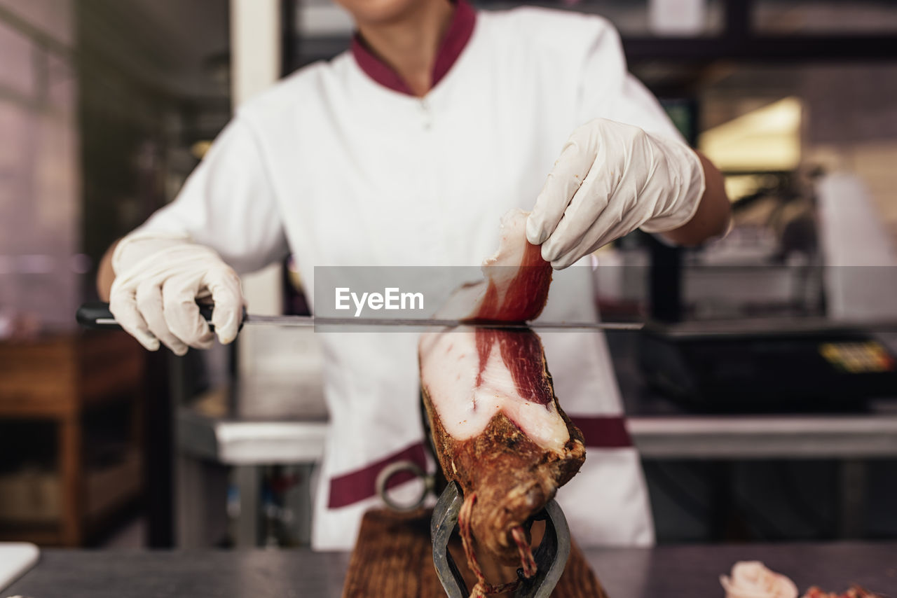 Midsection of man cutting meat in commercial kitchen