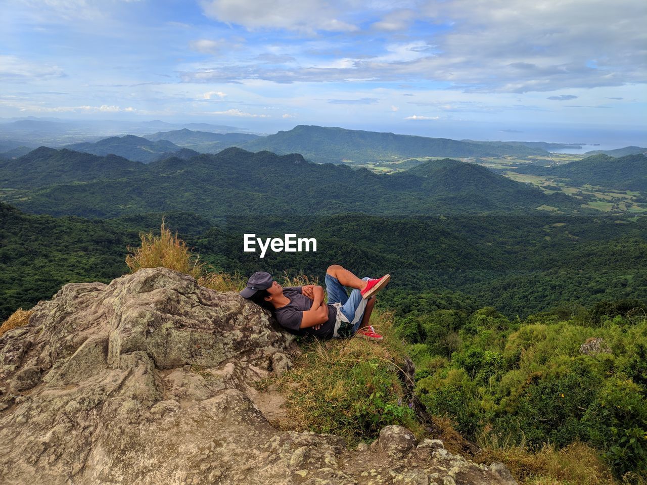 Man relaxing on mountain against sky