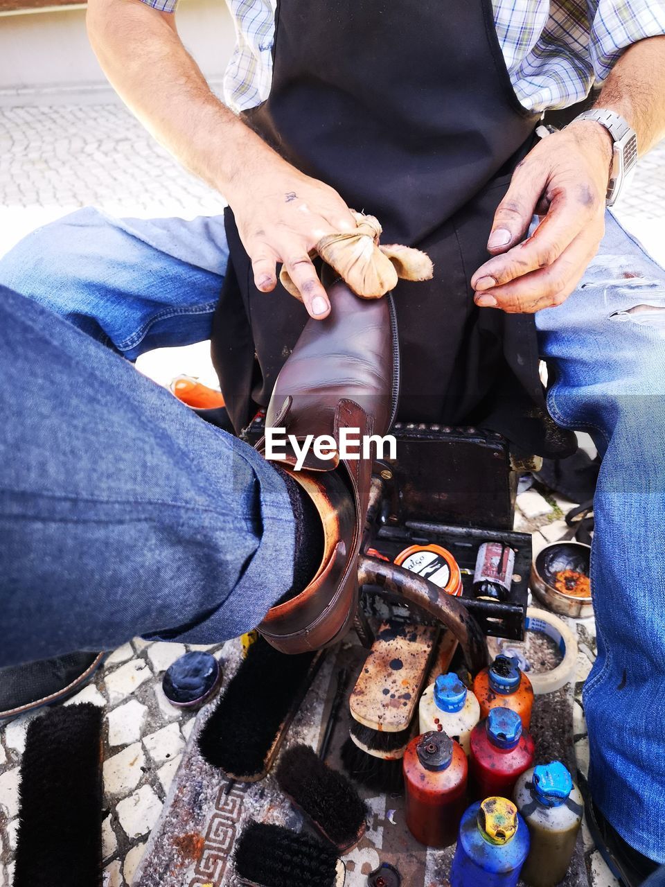 Man polishing shoe of customer in city