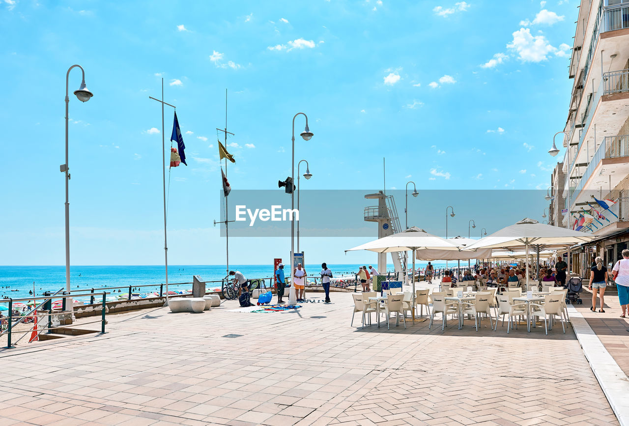 People at promenade by sea against sky
