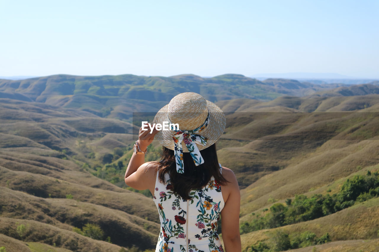 Rear view of woman looking at mountains against sky