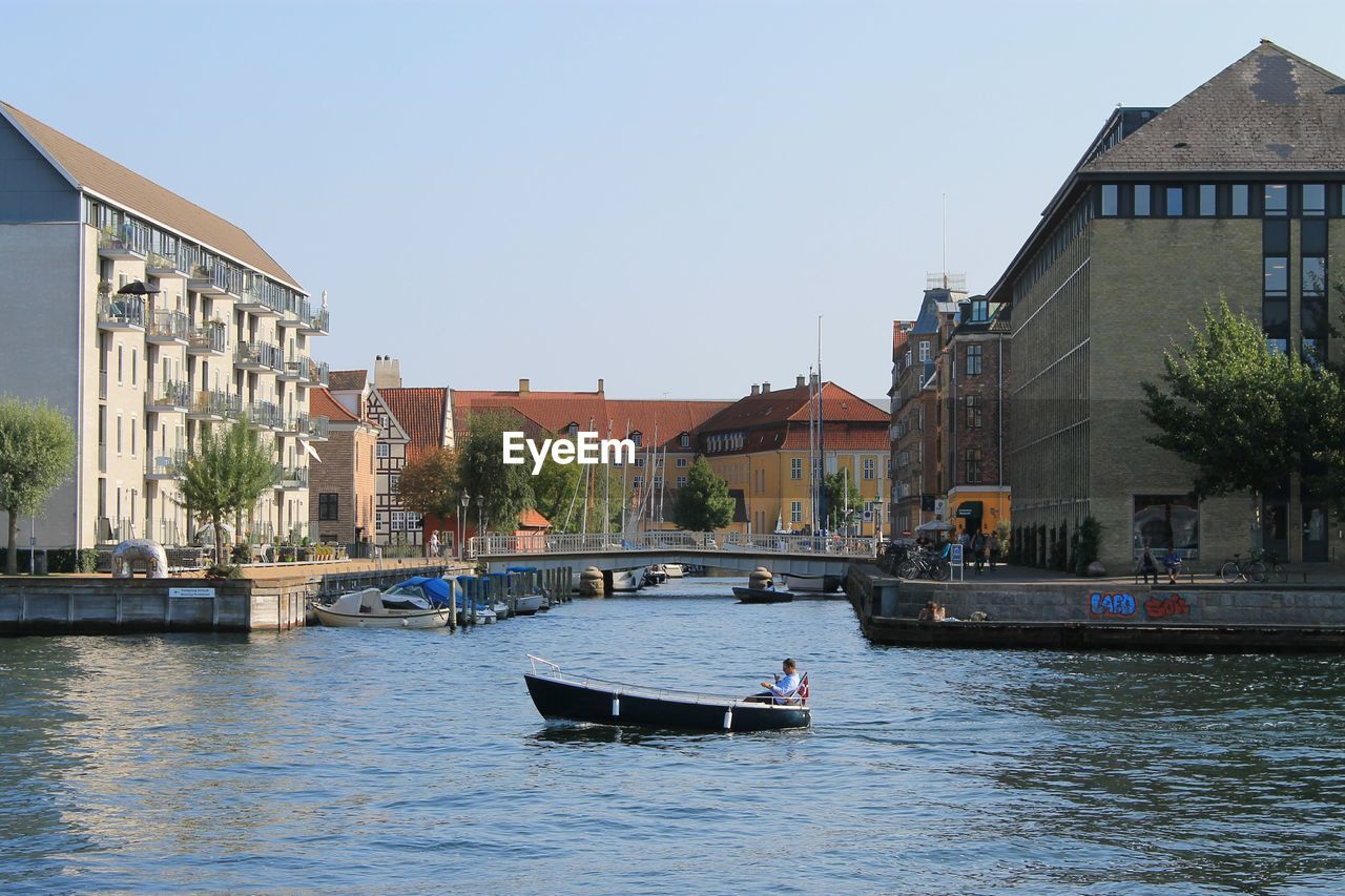 BOATS MOORED ON RIVER BY BUILDINGS AGAINST SKY