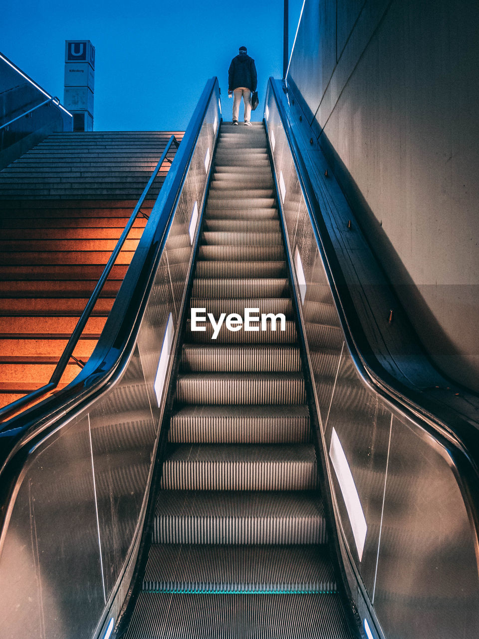 Low angle view of man standing on escalator at dusk