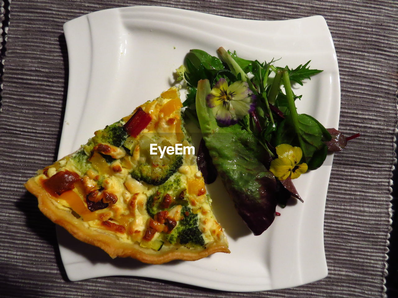 Close-up of pizza with salad in plate on table