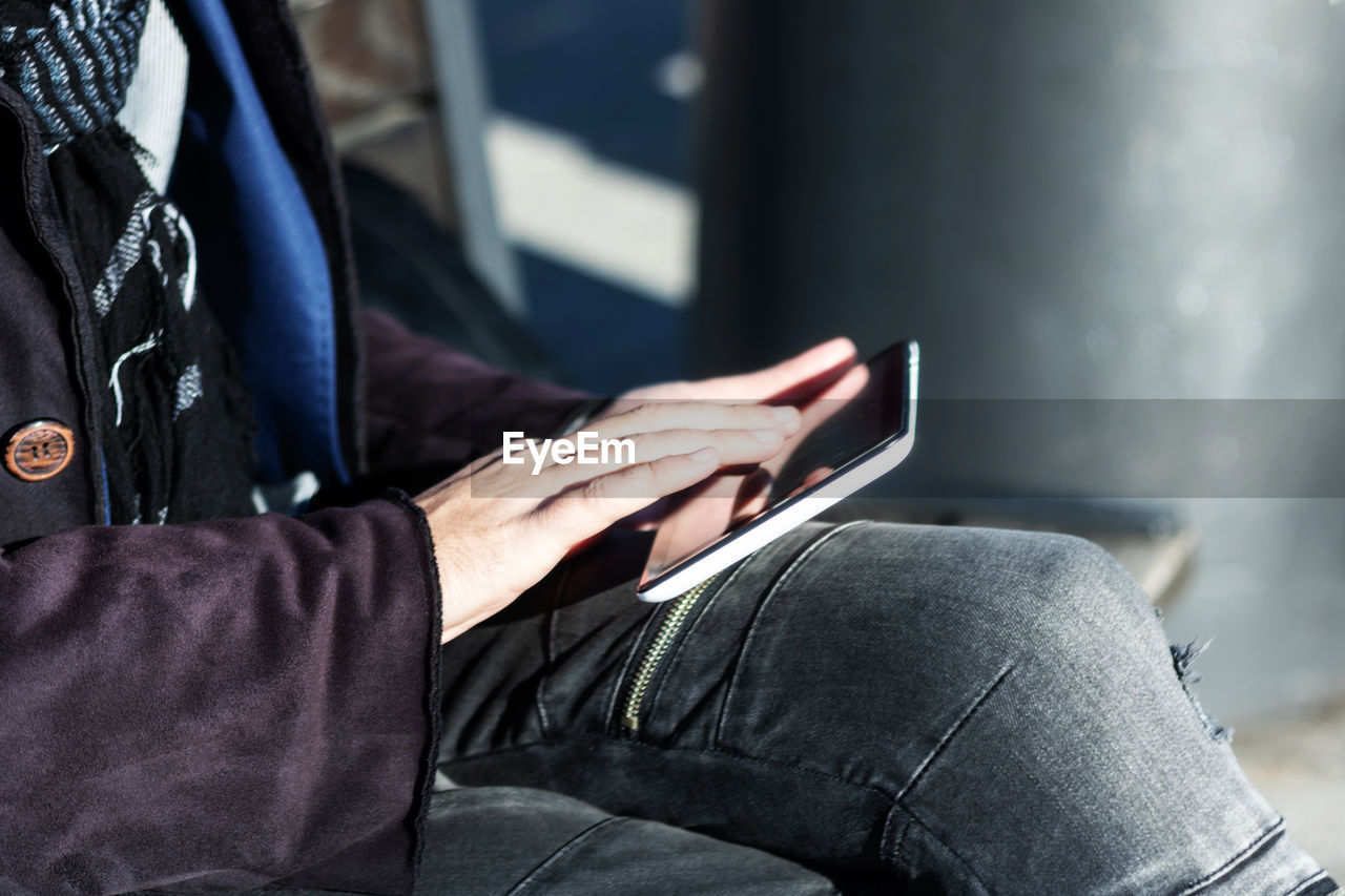 Close-up of man surfing the net on touchpad outdoors.