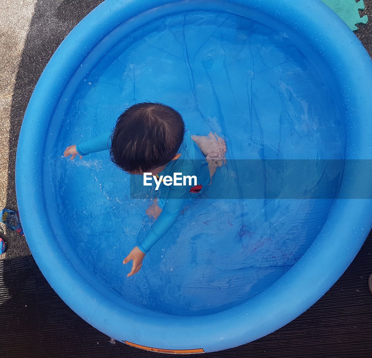 High angle view of boy playing in inflatable wading pool
