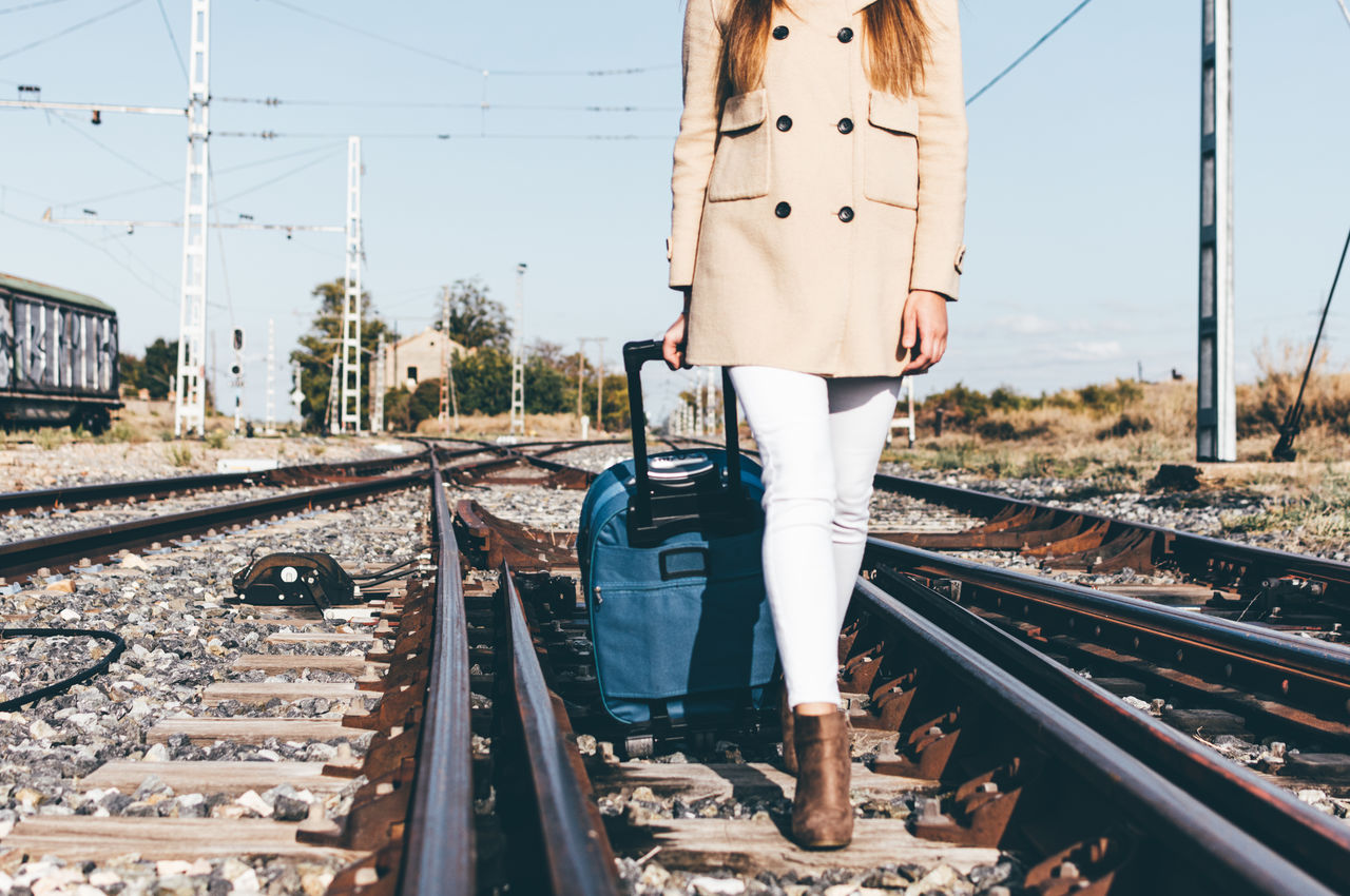 Low section of woman walking on railroad track