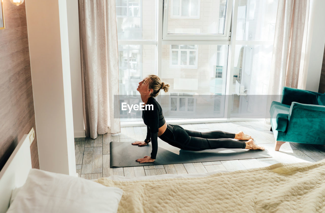 Side view of woman practicing yoga at home