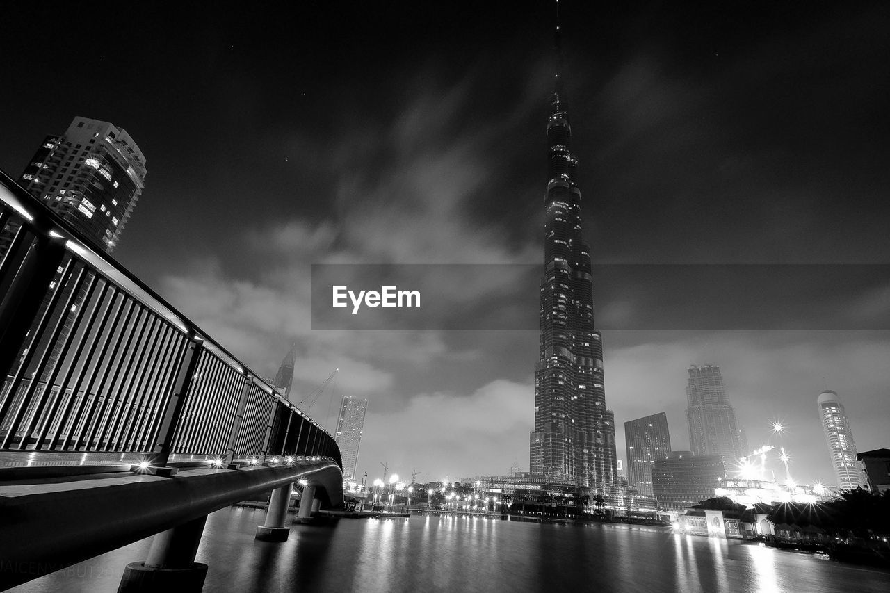 Low angle view of burj khalifa by sea against sky at night