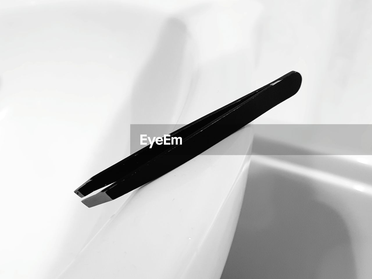 Close-up of tweezers on white ceramics