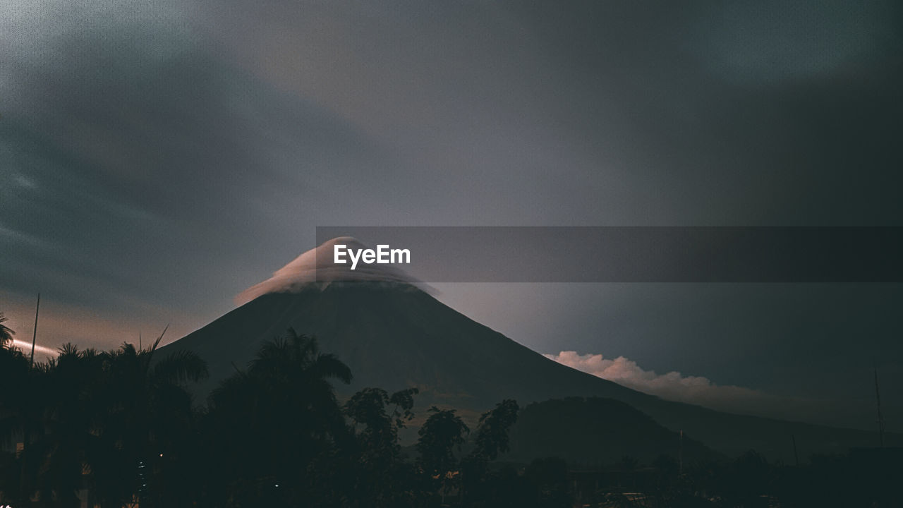 Scenic view of snowcapped mountains against sky . the mayon volcano under umbrella clouds