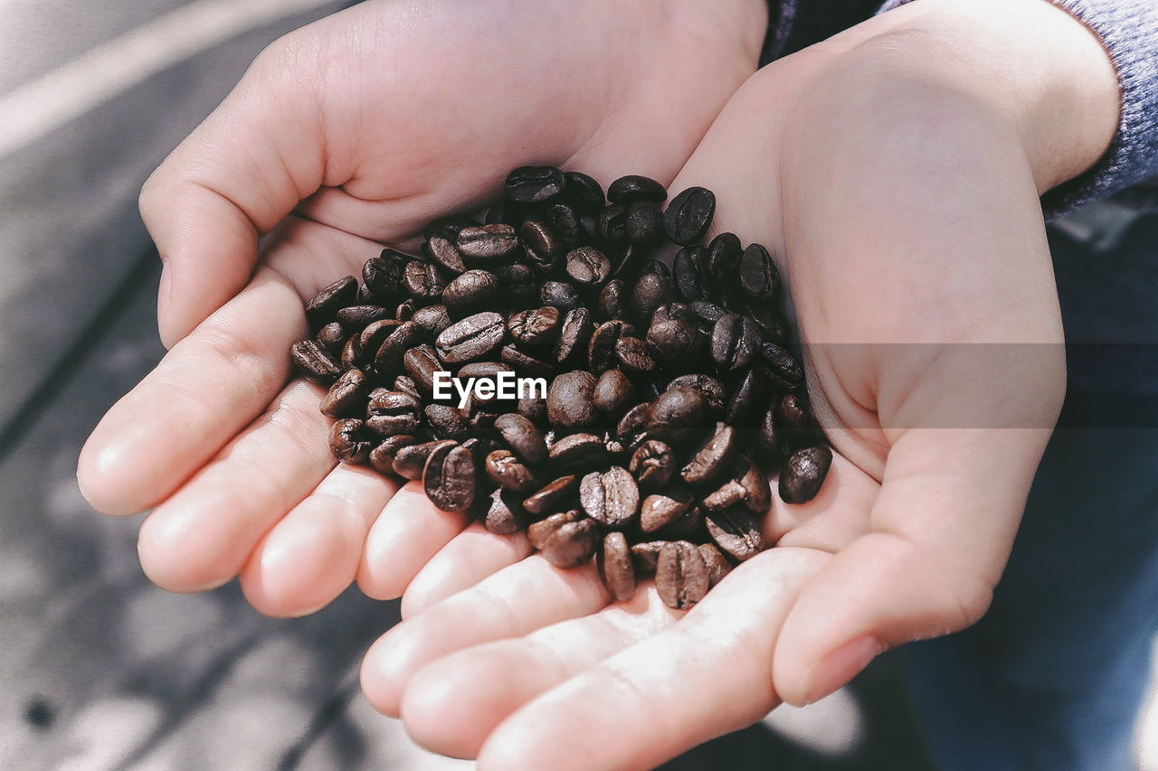 Midsection of person holding coffee beans