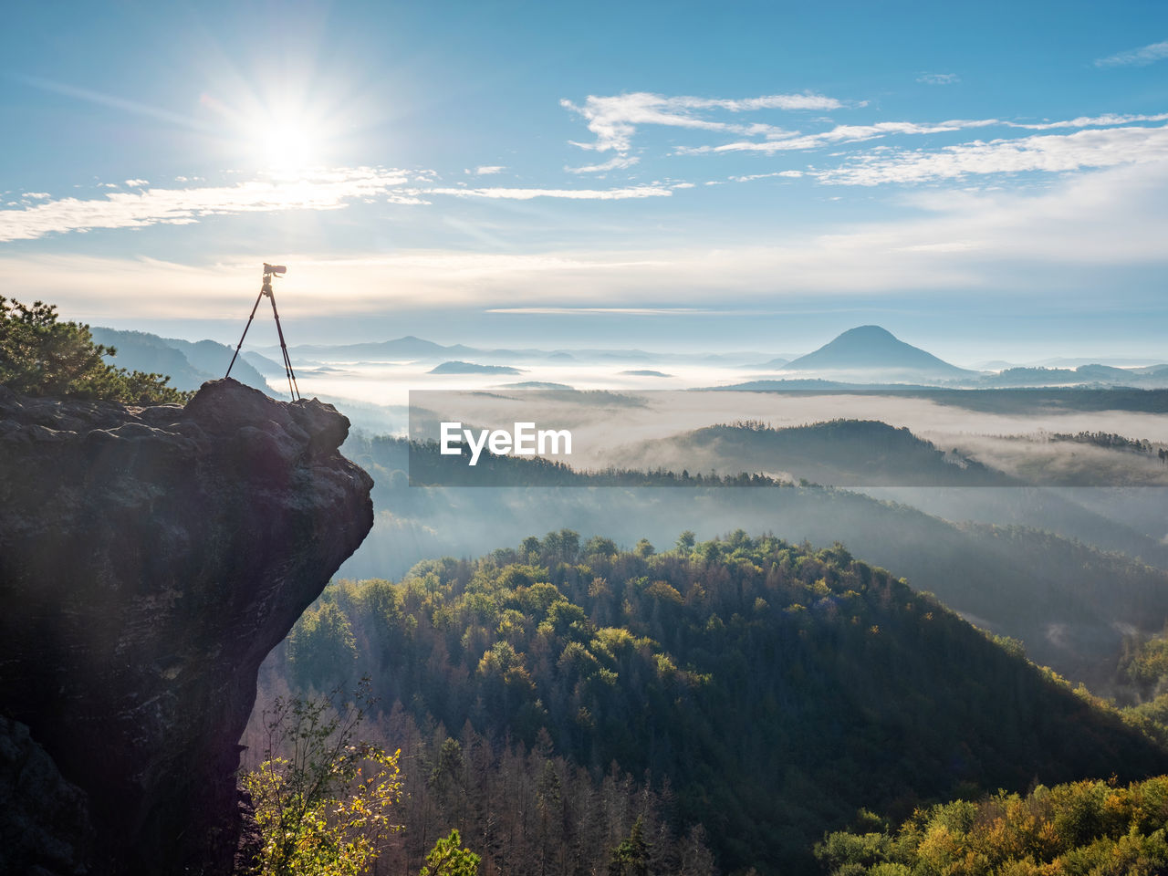 Camera stand on tripod photographing mountain, blue sky and foggy landscape. mountains background