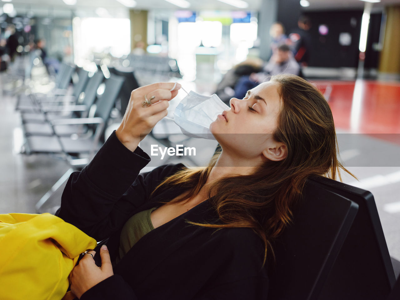 Woman removing mask while sitting at airport