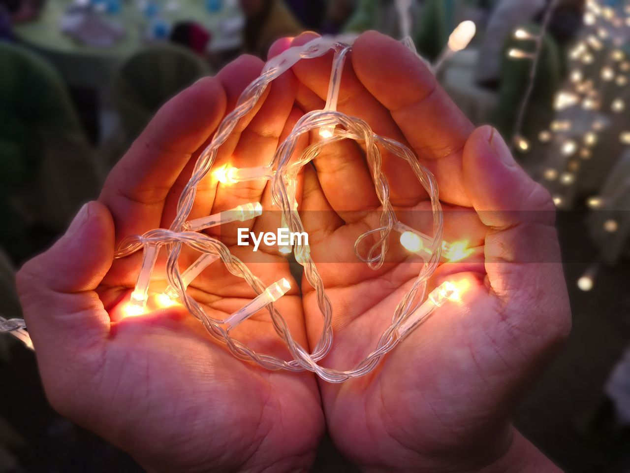 Cropped hands holding illuminated string lights