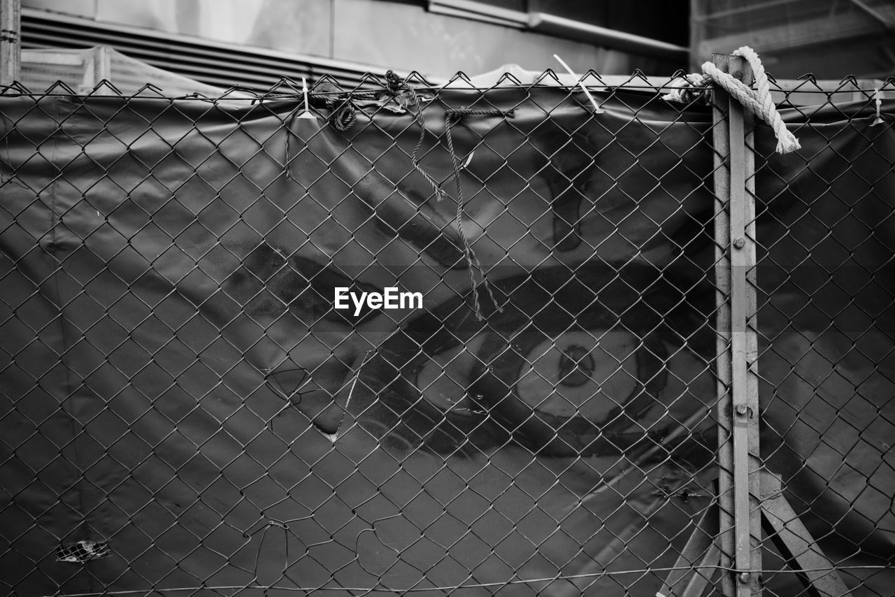 CLOSE-UP OF BARBED WIRE FENCE ON CHAINLINK OF METAL