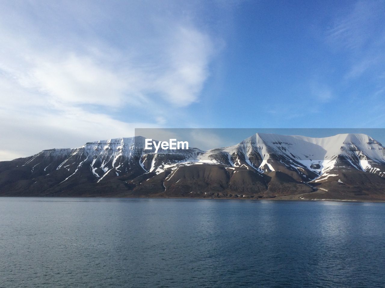 Scenic view of snowcapped mountain by sea against sky