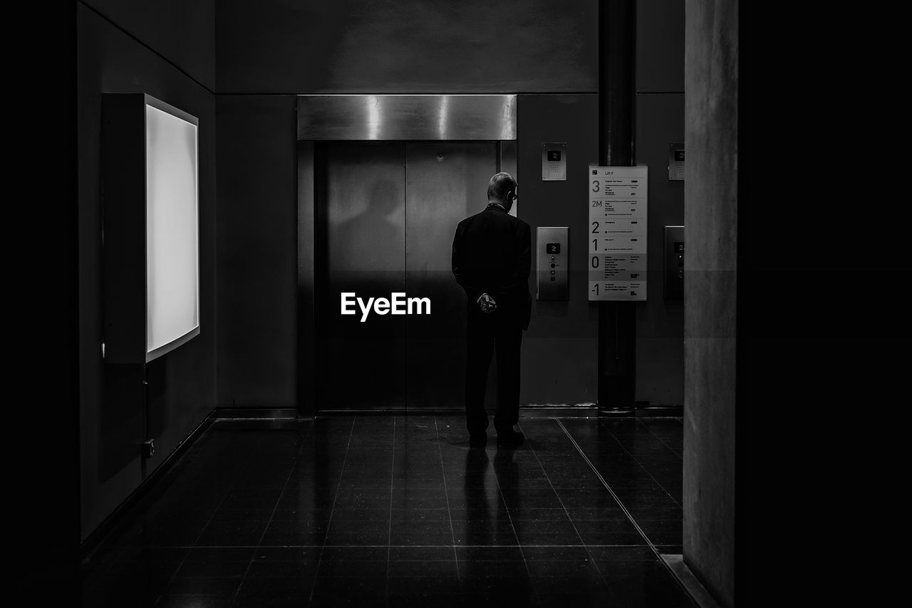 Rear view of man standing by entrance of elevator