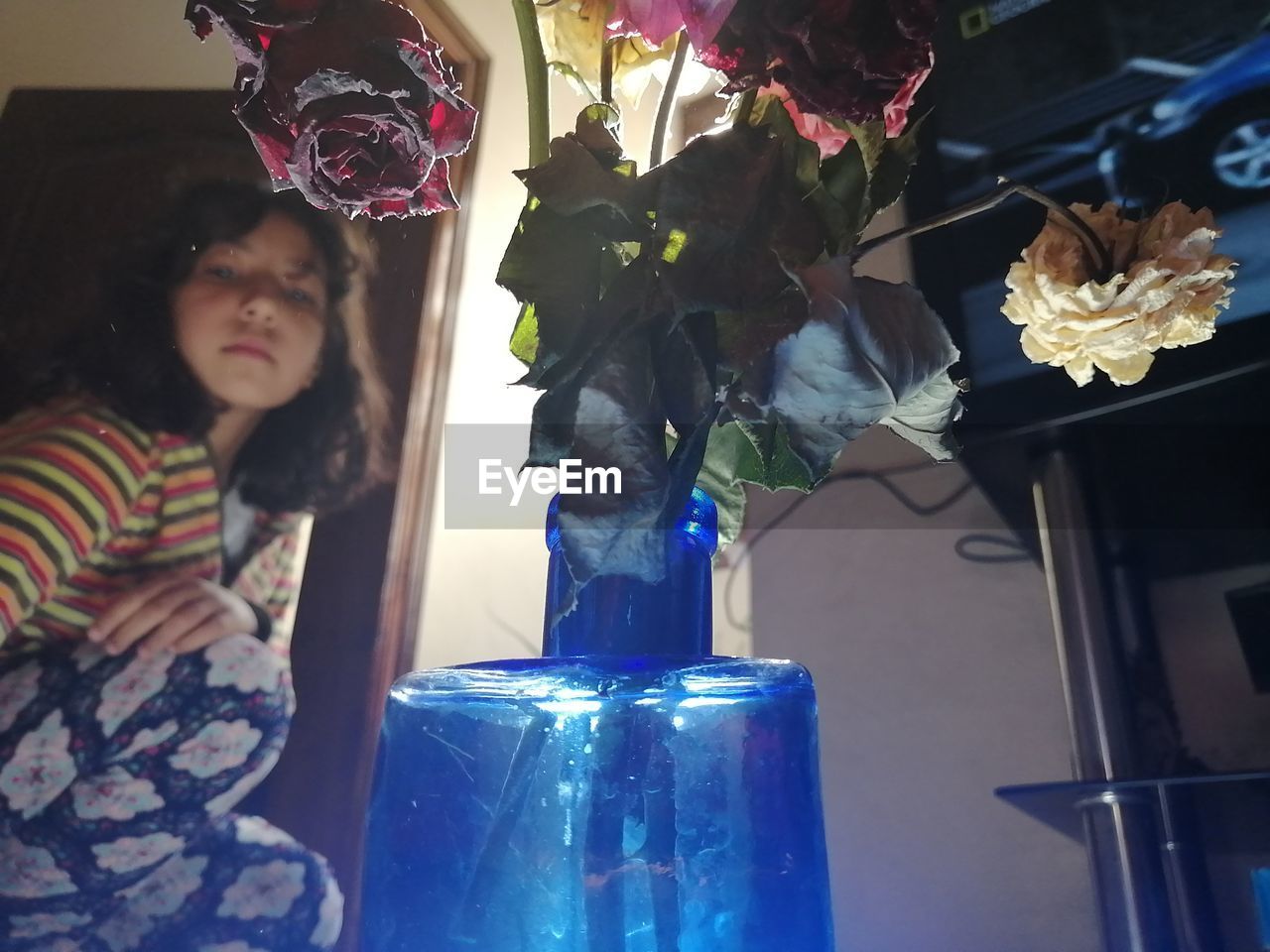 Midsection of girl behind dry flowers in vase at home