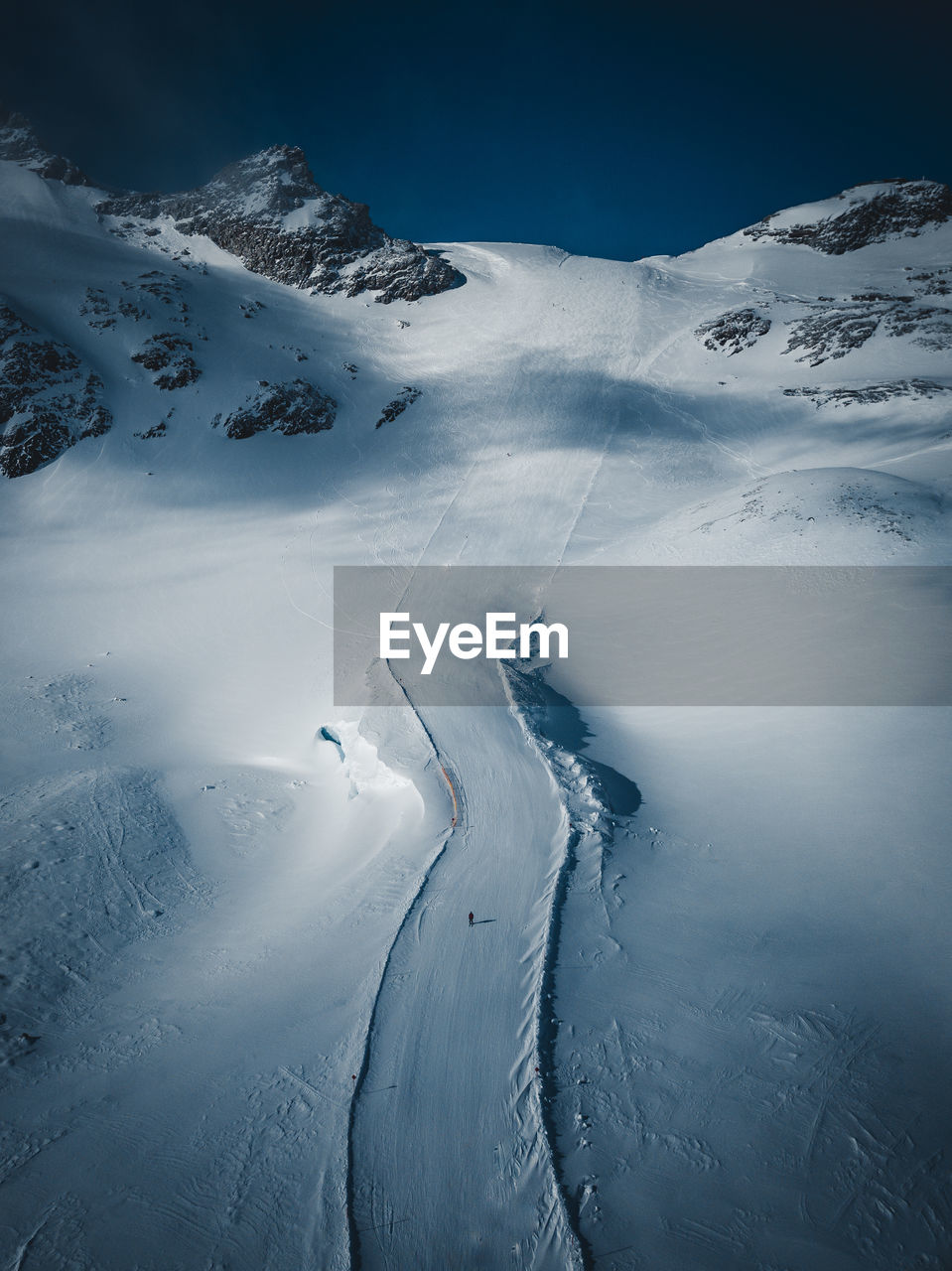 Aerial view of snowcapped mountains against sky with one person in middle