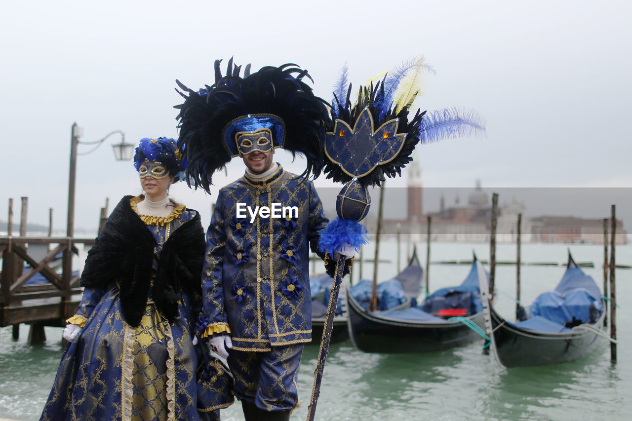 People wearing venetian masks and costume by grand canal